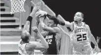  ?? CHRIS CARLSON/AP ?? Hornets forward P.J. Washington blocks a shot by Heat forward Jimmy Butler as center Bismack Biyombo converges during the second half of Friday’s game in Charlotte, North Carolina.