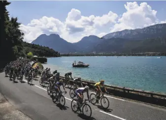  ?? Jeff Pachoud / AFP / Getty Images ?? Belgium’s Greg Van Avermaet, wearing the overall leader’s yellow jersey, and the pack ride along Lake Annecy in the French Alps during the 10th stage of the Tour de France.