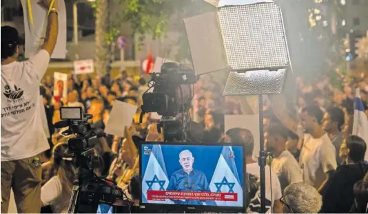  ?? ALEXI J. ROSENFELD (GETTY) ?? Una televisión en medio de una protesta para pedir la liberación de los rehenes israelíes emitía una intervenci­ón de Benjamín Netanyahu, el 18 de noviembre en Tel Aviv.