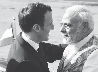  ?? MONEY SHARMA / AFP / GETTY IMAGES ?? India’s Prime Minister Narendra Modi, right, greets France’s President Emmanuel Macron upon his arrival at the Presidenti­al Palace in New Delhi on Saturday — a welcome that sharply contrasted the cool one given Justin Trudeau.