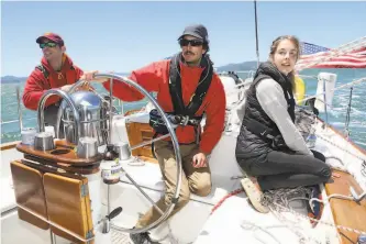  ?? Liz Hafalia / The Chronicle ?? Above: Airbnb hosts Mitchell Andrus (center) and Quincey Cummings (right) live and offer multiday tours on their 46foot sailboat, the Esprit, in Berkeley.
Top: Their operation, Q+M Travels, offers visitors sailing trips around San Francisco Bay through Airbnb Adventures.
Right: Panda, the seafaring cat, keeps an eye on things.