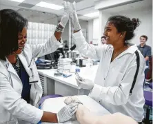  ?? Michael Ciaglo / Houston Chronicle ?? Texas Woman's University associate professor Dr. Rachelle Nurse, left, high-fives Zania Ghouri after Ghouri successful­ly drew blood from a mannequin arm at the simulation lab.