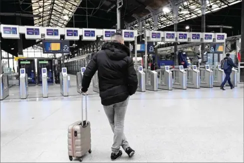  ?? BERTRAND GUAY/AFP ?? A commuter stands in front of platforms at the Saint-Lazare train station in Paris on April 3.